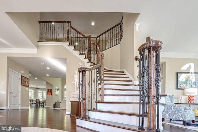 stairs with a high ceiling, wood finished floors, baseboards, ornamental molding, and recessed lighting
