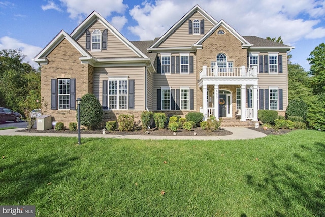 view of front of home featuring a balcony, a front yard, and brick siding
