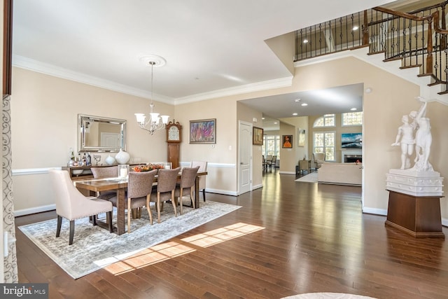 dining area featuring dark wood finished floors, crown molding, stairway, and a chandelier