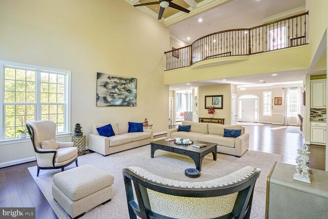 living area featuring dark wood finished floors, plenty of natural light, ornamental molding, and a ceiling fan
