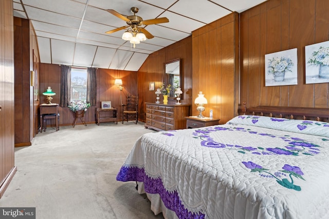 bedroom with wood walls, light colored carpet, and a ceiling fan