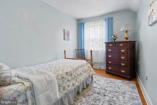 bedroom featuring wood finished floors, vaulted ceiling, and baseboards
