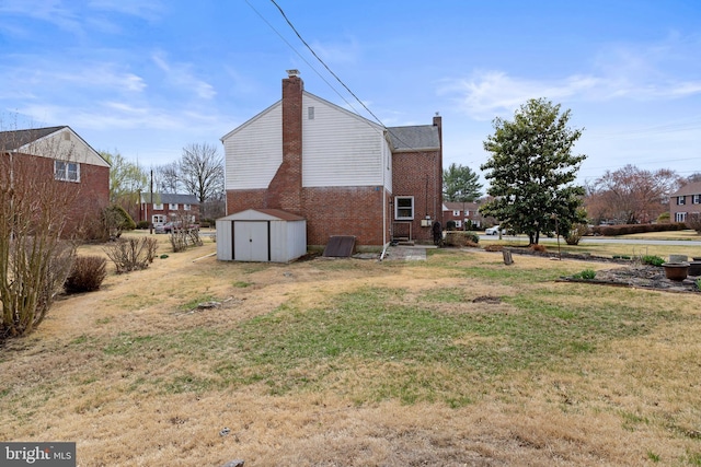 view of home's exterior with a chimney, brick siding, a shed, a yard, and an outdoor structure