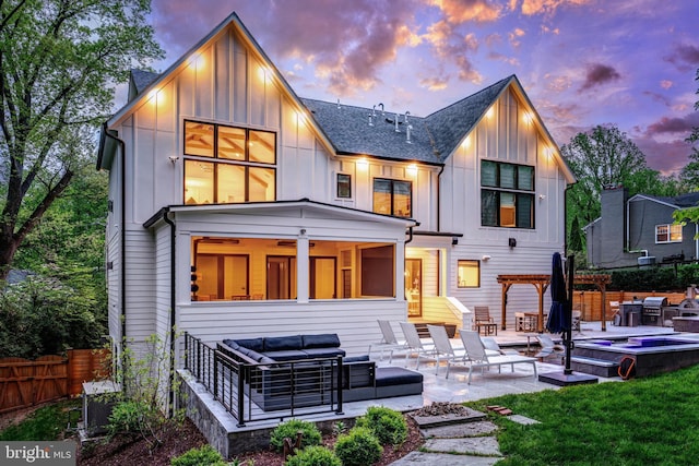 1544 Forest Villa Ln, Mclean, VA 22101 - back of house at dusk with board and batten siding, a jacuzzi, an outdoor living space, and a patio area