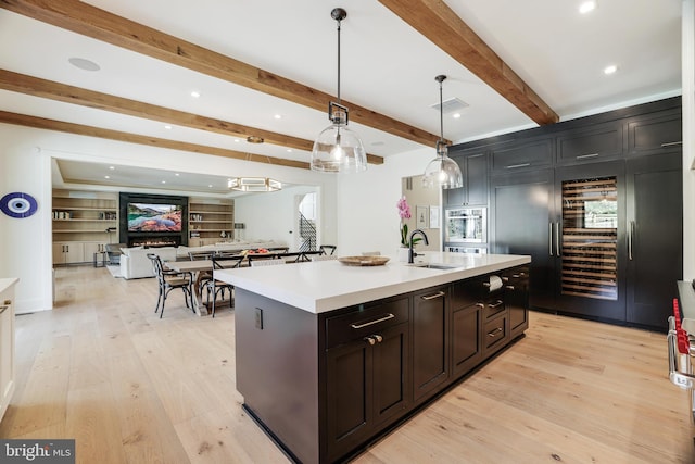 1544 Forest Villa Ln, Mclean, VA 22101 - kitchen featuring a sink, light countertops, an island with sink, light wood finished floors, and beam ceiling