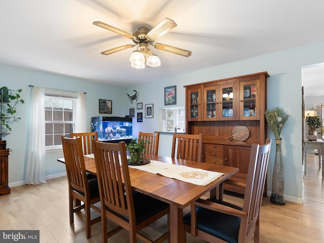 dining space with baseboards, ceiling fan, and light wood-type flooring
