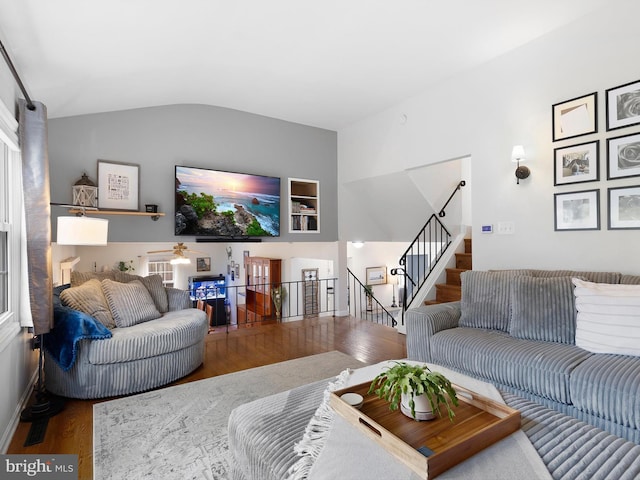 living area featuring plenty of natural light, stairway, vaulted ceiling, and wood finished floors
