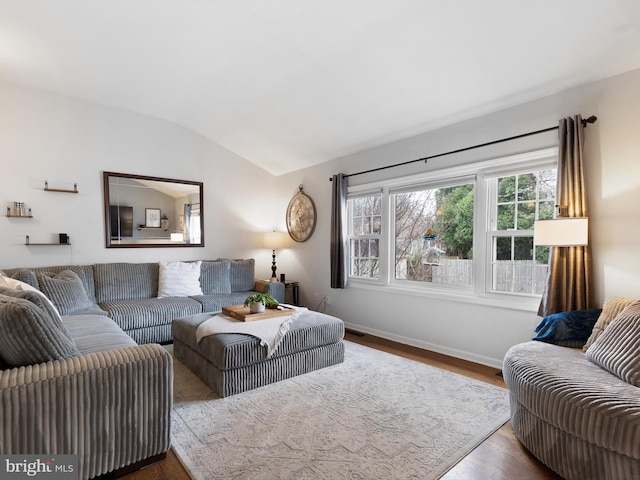 living area featuring baseboards, vaulted ceiling, and wood finished floors