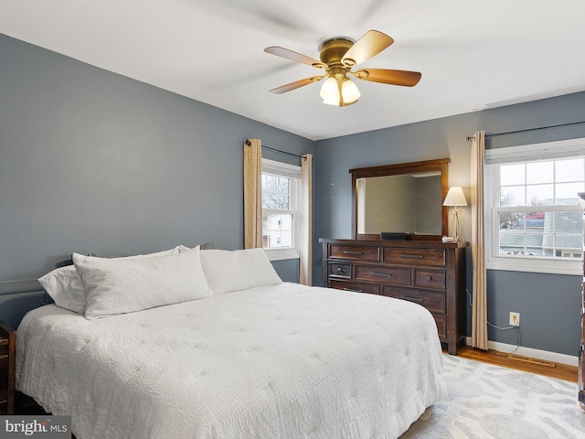 bedroom with a ceiling fan, light wood-style flooring, baseboards, and visible vents