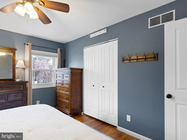 bedroom with baseboards, dark wood-style floors, ceiling fan, visible vents, and a closet