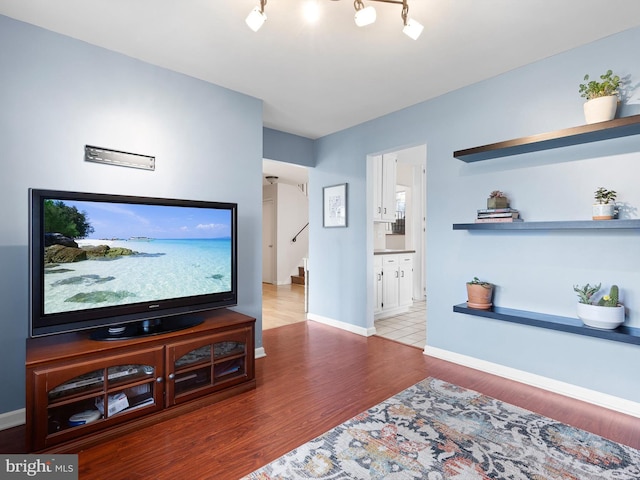 living area with baseboards, stairs, and wood finished floors