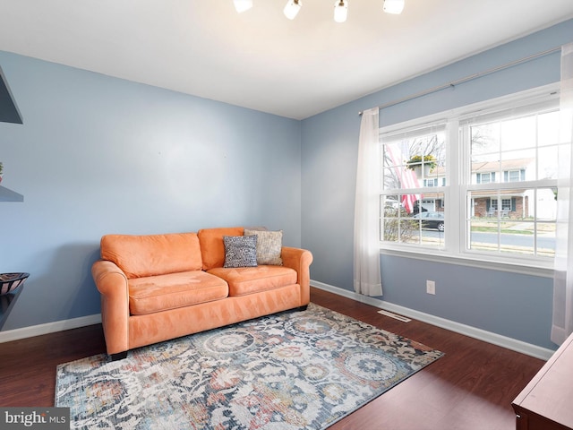 living room featuring visible vents, baseboards, and wood finished floors