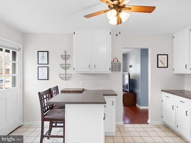 kitchen with white cabinetry, dark countertops, ceiling fan, and light tile patterned floors