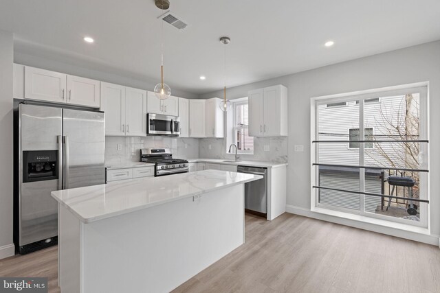 1404 S Patton St, Philadelphia, PA 19146 - kitchen with white cabinets, visible vents, light wood finished floors, stainless steel appliances, and backsplash