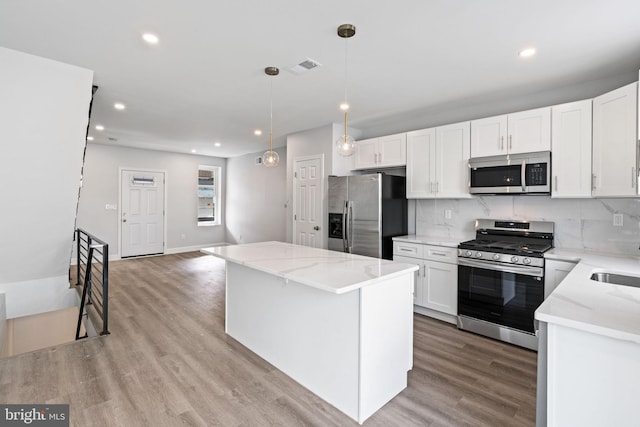 1404 S Patton St, Philadelphia, PA 19146 - kitchen featuring decorative backsplash, white cabinetry, light wood-type flooring, and appliances with stainless steel finishes