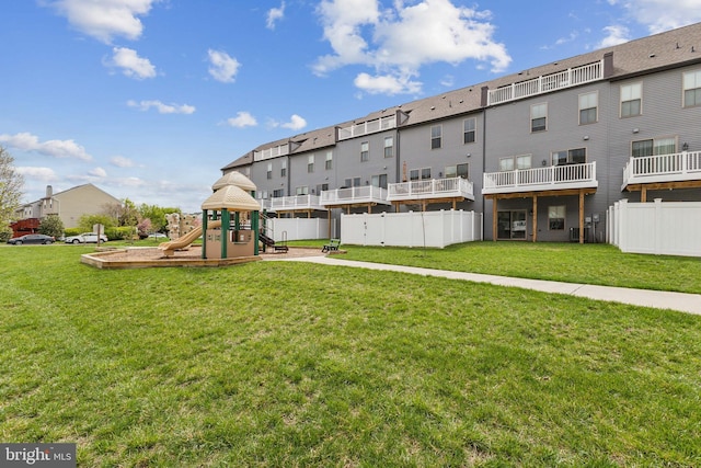 back of house with a lawn, fence, and playground community