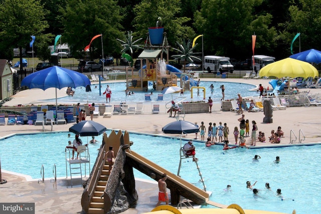 pool featuring fence, a patio area, and a water slide