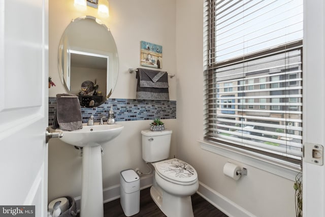 half bath featuring backsplash, toilet, wood finished floors, and baseboards