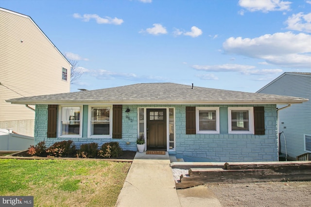 bungalow-style home with a front lawn, stone siding, and a shingled roof