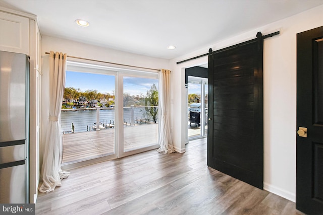 empty room with recessed lighting, a barn door, baseboards, and wood finished floors