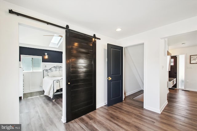 bedroom featuring a barn door, baseboards, and wood finished floors