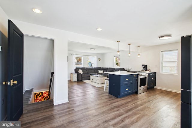 kitchen featuring a peninsula, blue cabinetry, gas range, dark wood-type flooring, and a breakfast bar area