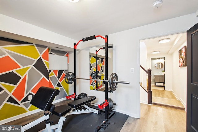 workout area with baseboards and wood finished floors