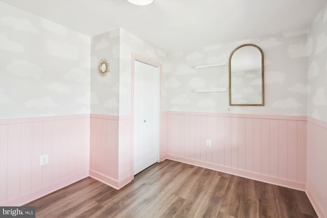 unfurnished room featuring a wainscoted wall and wood finished floors