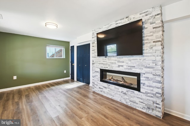 unfurnished living room featuring wood finished floors, a fireplace, and baseboards