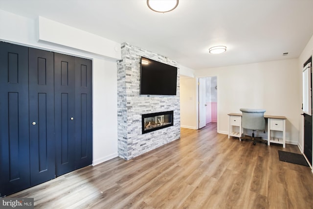 office with light wood-style flooring, baseboards, and a stone fireplace