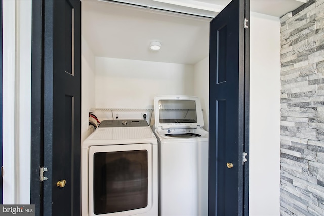 laundry area with brick wall, laundry area, and washing machine and clothes dryer