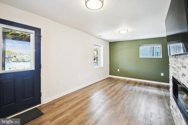 entryway with a stone fireplace, baseboards, and wood finished floors