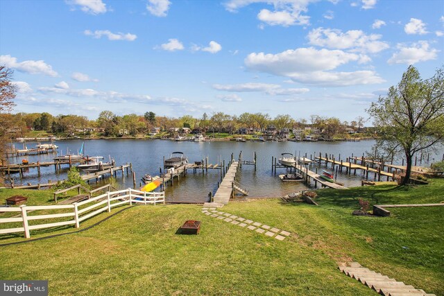 dock area with a water view, a lawn, and boat lift
