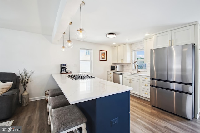 kitchen with a sink, a breakfast bar, a peninsula, stainless steel appliances, and backsplash
