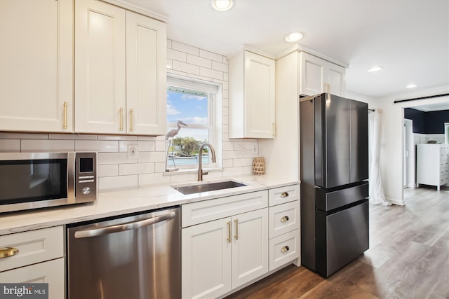 kitchen featuring a sink, appliances with stainless steel finishes, light stone countertops, dark wood-type flooring, and decorative backsplash