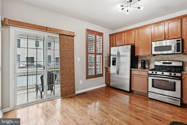 25149 Shultz Ter, Chantilly, VA 20152 - kitchen with stainless steel appliances, light wood-style flooring, baseboards, backsplash, and a chandelier