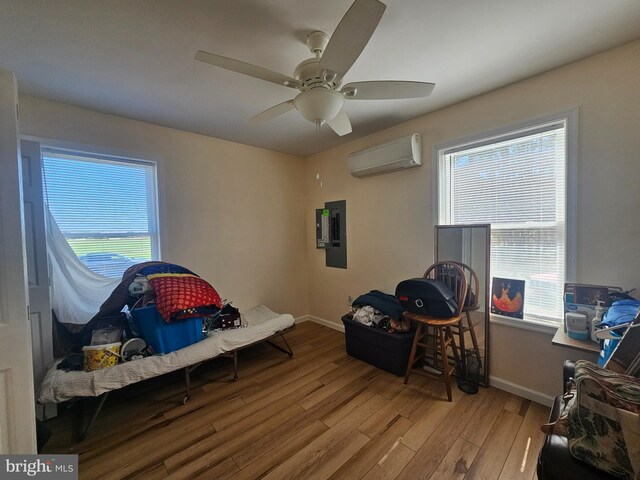 bedroom featuring baseboards, wood finished floors, a wall unit AC, and electric panel