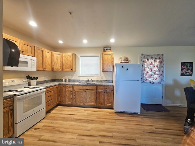 kitchen with recessed lighting, white appliances, a sink, light wood finished floors, and brown cabinetry