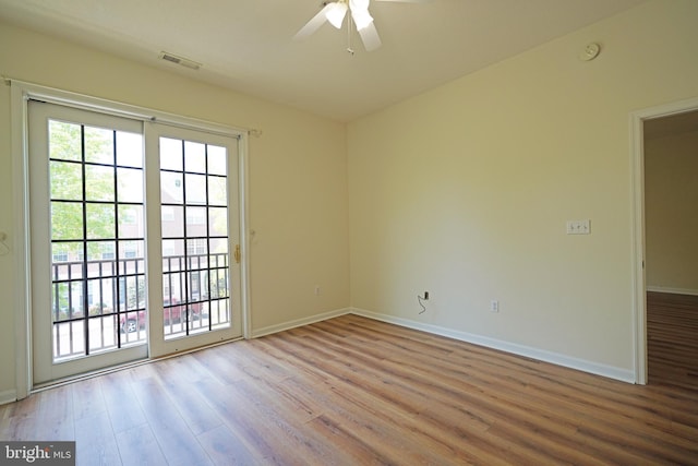 empty room with wood finished floors, a ceiling fan, baseboards, and a smoke detector