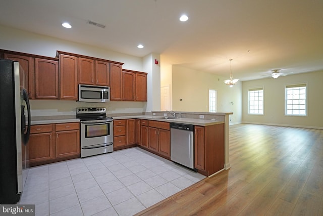 kitchen with stainless steel appliances, a peninsula, a chandelier, light countertops, and recessed lighting
