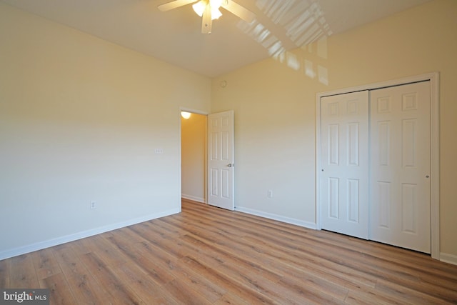 unfurnished bedroom featuring wood finished floors, baseboards, a closet, and lofted ceiling