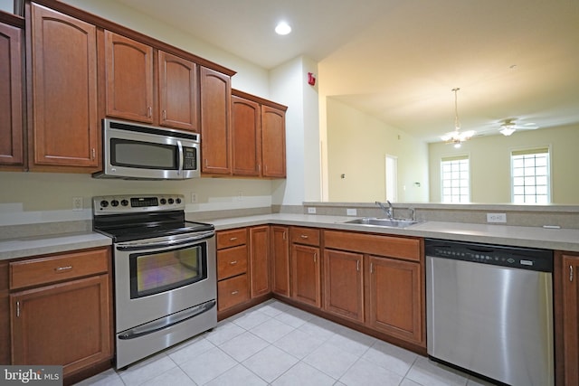kitchen with appliances with stainless steel finishes, a sink, light tile patterned floors, light countertops, and brown cabinetry