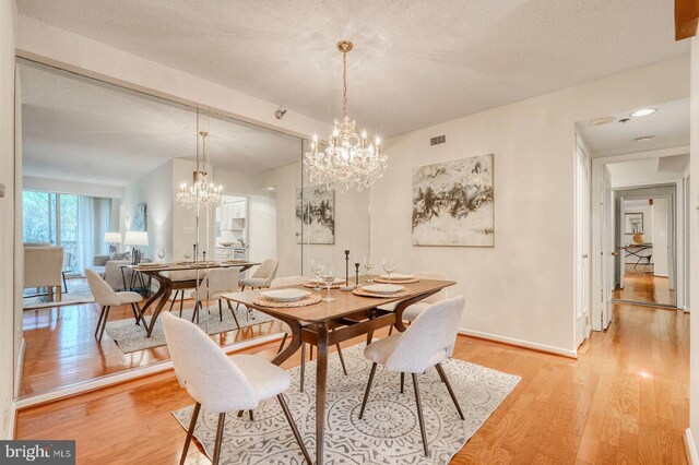 dining room with visible vents, baseboards, a notable chandelier, a textured ceiling, and light wood-style flooring