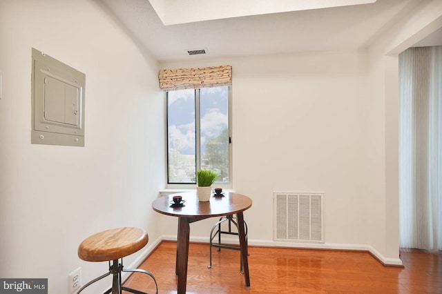 dining area with wood finished floors, electric panel, baseboards, and visible vents