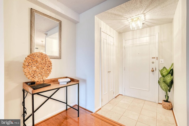 foyer with baseboards and a textured ceiling