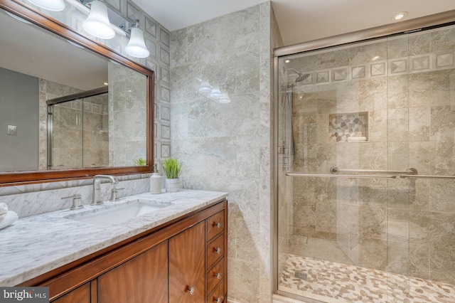 bathroom featuring vanity, tile walls, and a stall shower