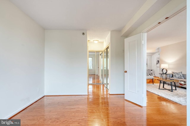 spare room with baseboards and light wood-style floors