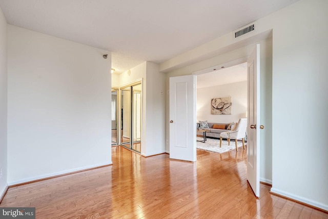 empty room with light wood finished floors, baseboards, and visible vents