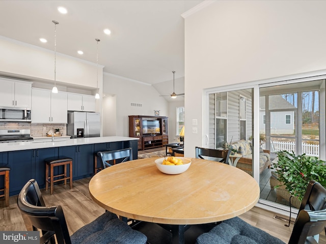 dining area featuring a ceiling fan, crown molding, light wood-style floors, and visible vents