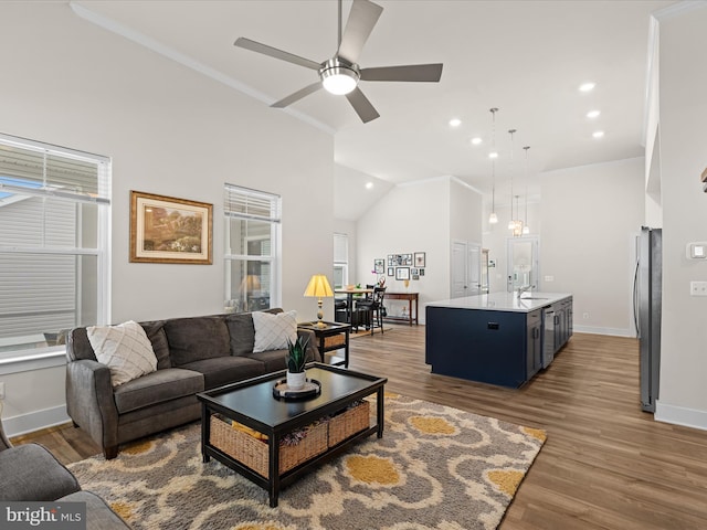 living area featuring baseboards, ornamental molding, wood finished floors, and a ceiling fan